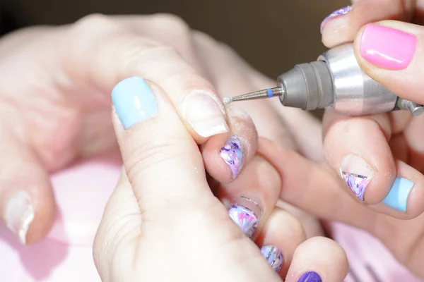 manicure master cuts the cuticle on the client\'s arm