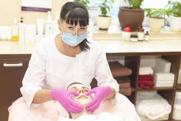 the girl at the reception at the beautician makes facial cleansing