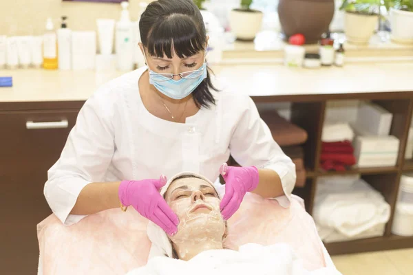 the girl at the reception at the beautician makes facial cleansing