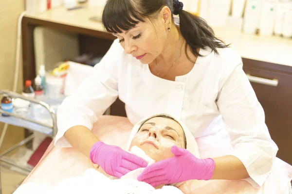 the girl at the reception at the beautician makes facial cleansing