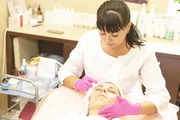 the girl at the reception at the beautician makes facial cleansing