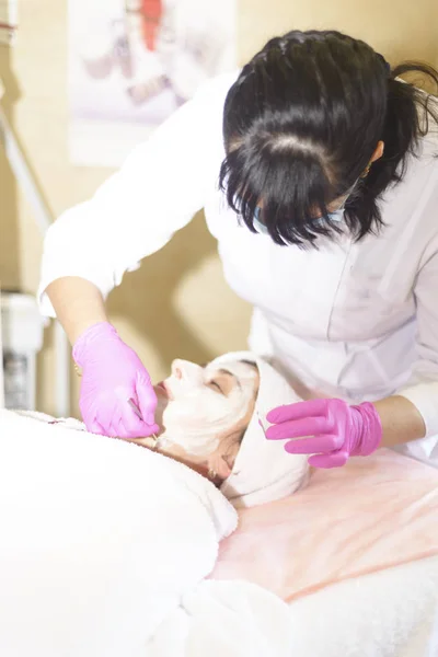 the girl at the reception at the beautician makes facial cleansing