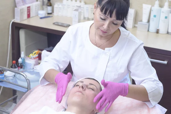 the girl at the reception at the beautician makes facial cleansing