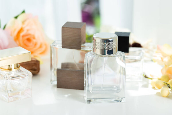 Парфюмерные бутылки на фоне цветов
