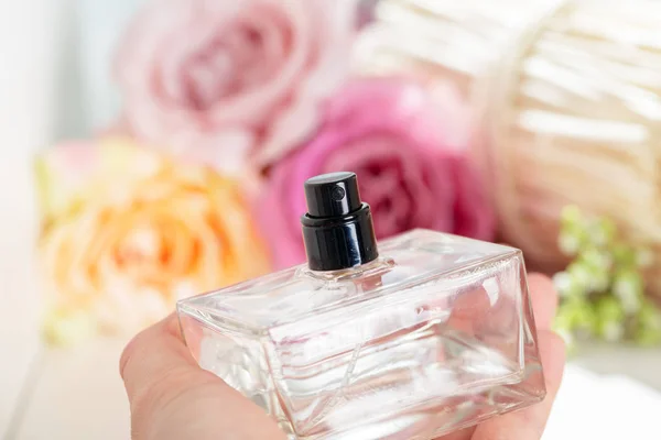 Weibliche Hand Hält Parfümflasche Auf Blumen Hintergrund — Stockfoto