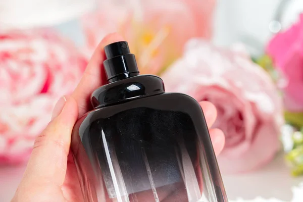Weibliche Hand Hält Parfümflasche Auf Blumen Hintergrund — Stockfoto