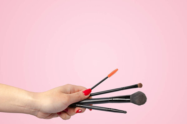 Женщина рука держа косметический инструмент изолирован на цветном фоне
