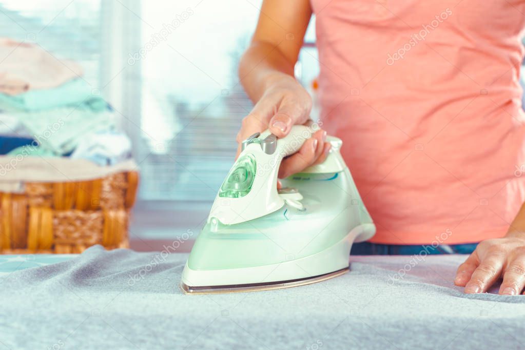 Close up view of woman ironing clothes on ironing board