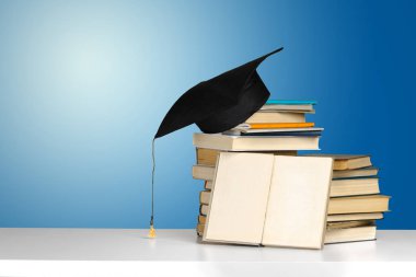 Bir yığın kitap ve ahşap masa üzerine şapka