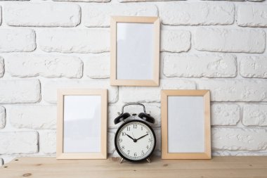boş beyaz resim çerçevesi ile çalar saat tuğla duvar