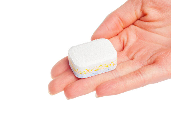 female hand holding dishwasher tablet isolated on white background, close-up 