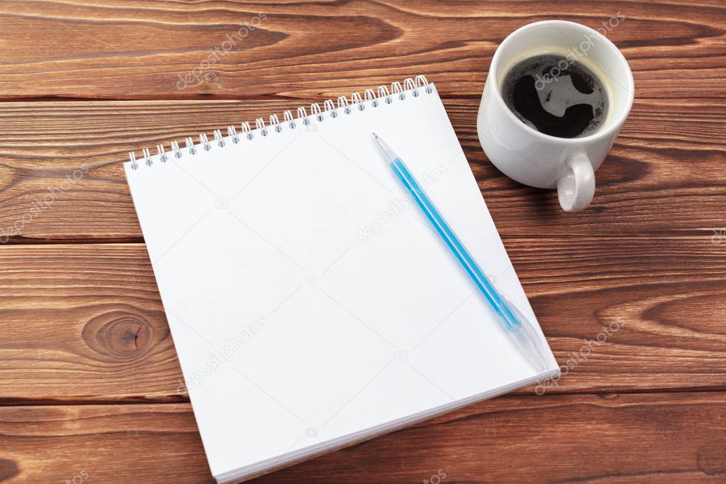 Office desk table top view. Notepad with blank pages on wooden table