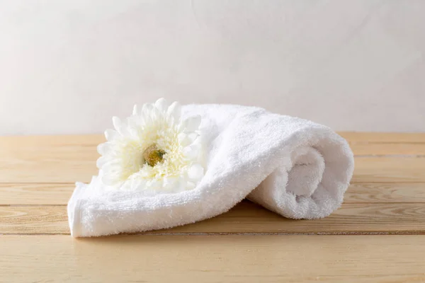 towels roll with flower on wooden table