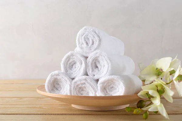white clean towels roll with flower on wooden table