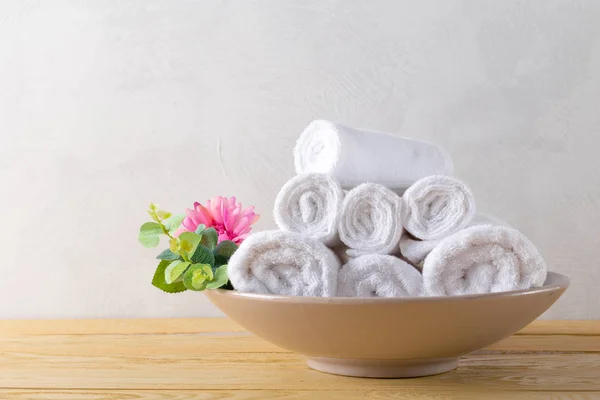 white clean towels roll with flower on wooden table