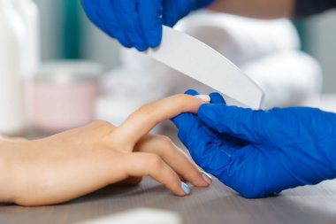 Kadın elleri güzellik salonunda manikür yaptırıyor.