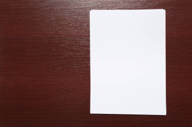 Ahşap masa üzerinde beyaz iş kartı. Boş dikey A4.
