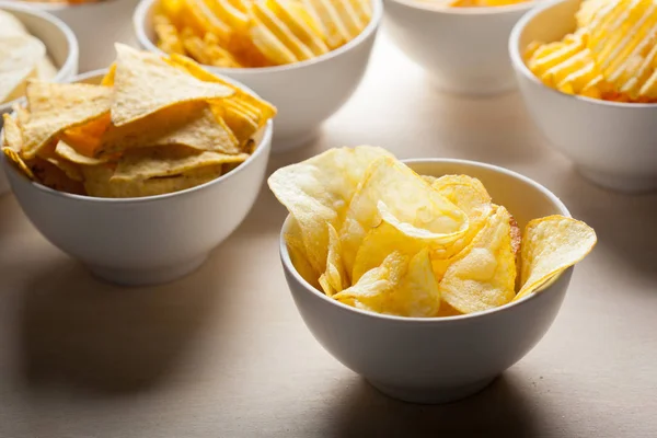 Yellow crispy potato chips in bowls on table