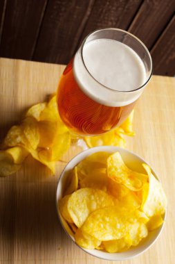 Lager bira cam ve ahşap arka plan üzerinde gevrek patates cipsi