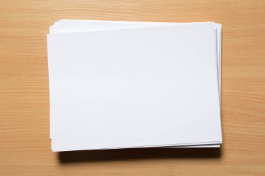 Ahşap masa üzerinde beyaz iş kartı. Boş dikey A4.