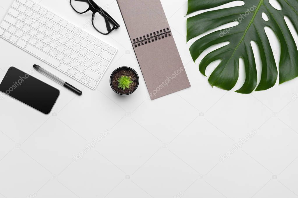 workspace with keyboard, palm leaf and accessories. Flat lay, top view copy space