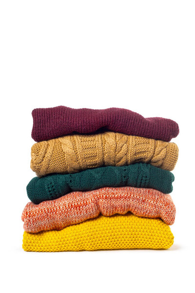 Stack of various sweaters isolated on white background