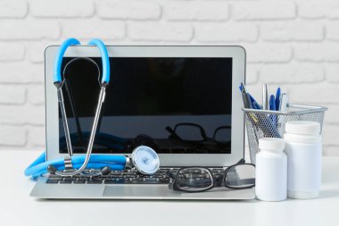 Stetoskop, dizüstü bilgisayar ve beyaz masa hapları