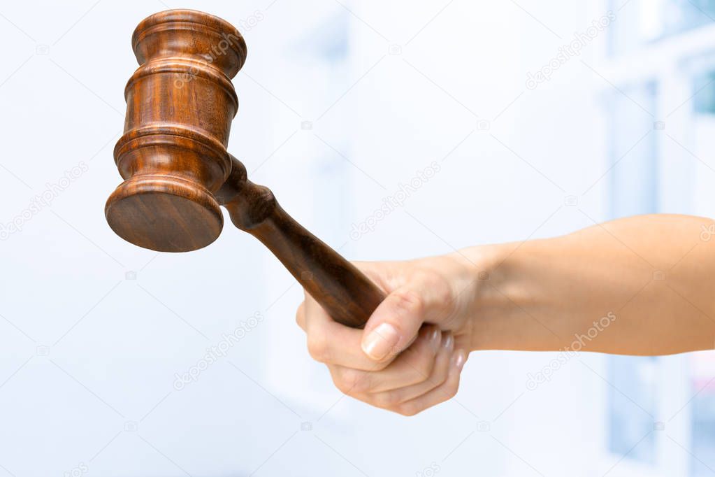 female hand holding wooden law gavel