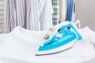 Kumaş arka planda elektrikli ütü ve gömlek.