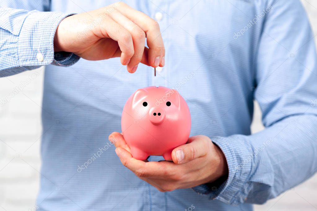 man putting coin in piggy bank