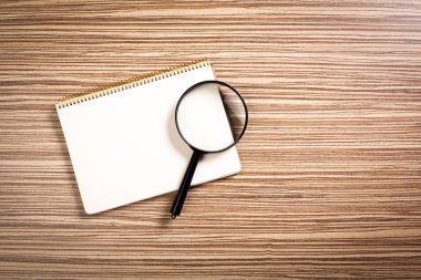 defter ve ahşap arka plan üzerinde büyüteç