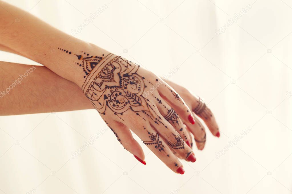 Red manicured hands with Mehndi 