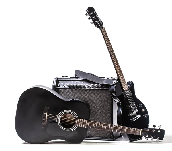 Black electro guitars and acoustic guitar isolated on white