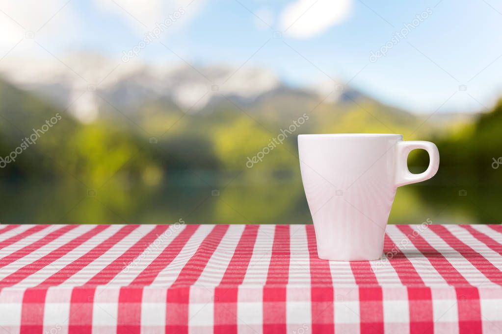Coffee cup on red checkered tablecloth