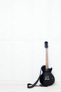guitar propped in front of a white wall  clipart