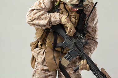 Kamuflajlı asker elinde tüfekle