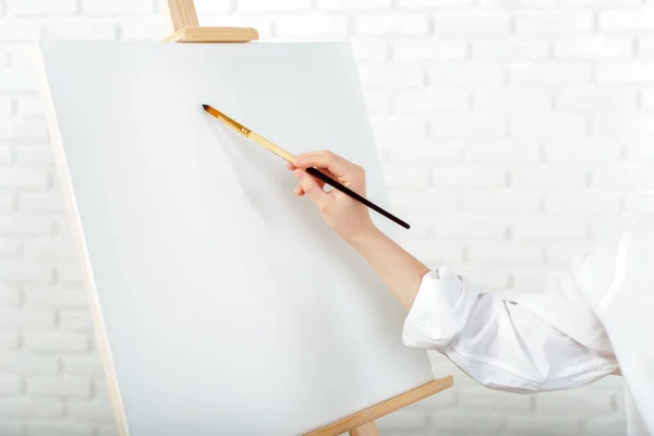 Young female artist painting picture in studio