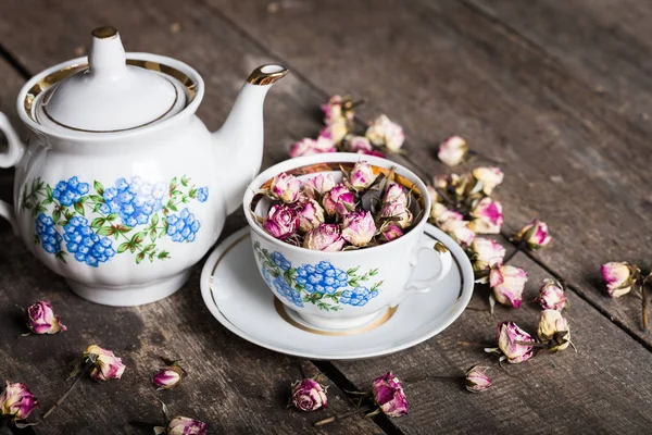 Vintage teapot and cup with blooming tea flowers on wooden background