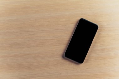 ahşap masa ve boş kopya alanı üstünde hareket eden telefon