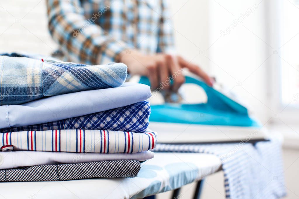 Closeup of woman ironing clothes on ironing board