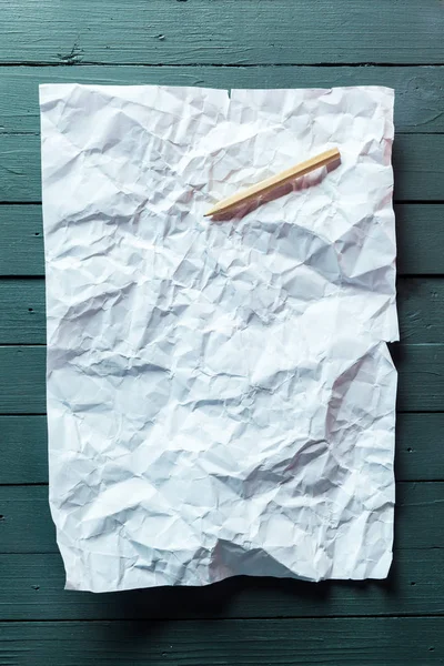 crumpled sheet of paper and pencil