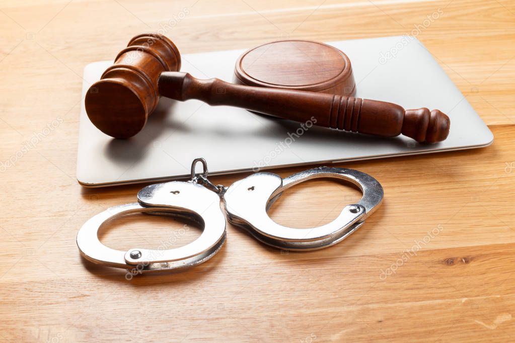 Gavel and handcuffs on wooden table background