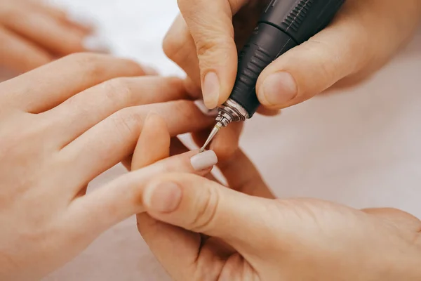 Manicurist with a milling cutter for manicure, close-up view