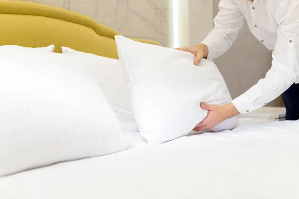 hotel staff setting up pillow on bed