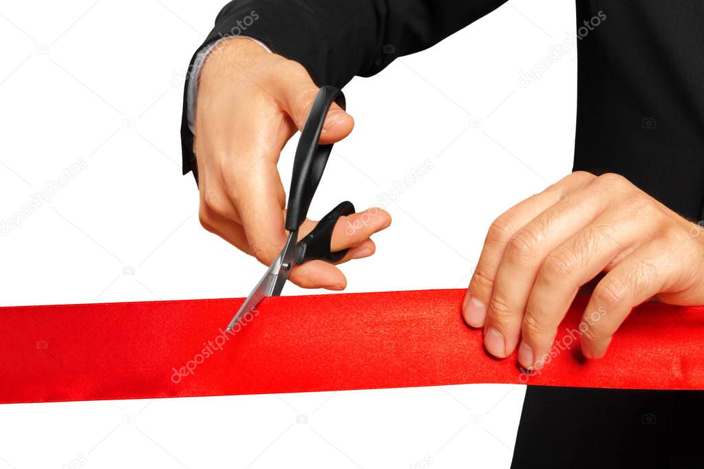 Scissors are cutting red ribbon or tape. Isolated on white background.