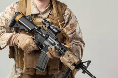 Kamuflajlı asker elinde tüfekle