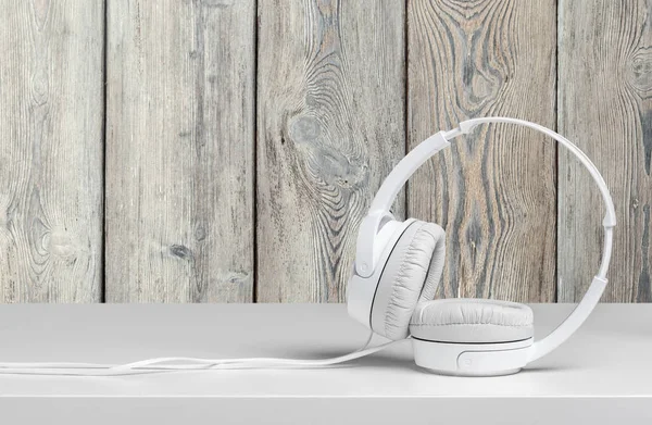 White headphones on table against wooden background