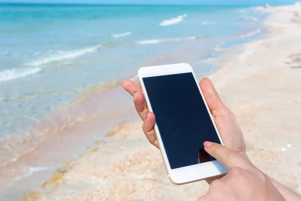 女性手在海滩使用智能手机 — 图库照片