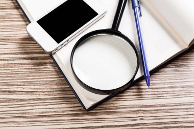 Cep telefonu ve ahşap masa üzerinde büyüteç ile çeşitli ofis, banka donatımı