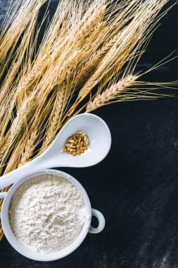 Siyah arka planda buğday kulakları ve un